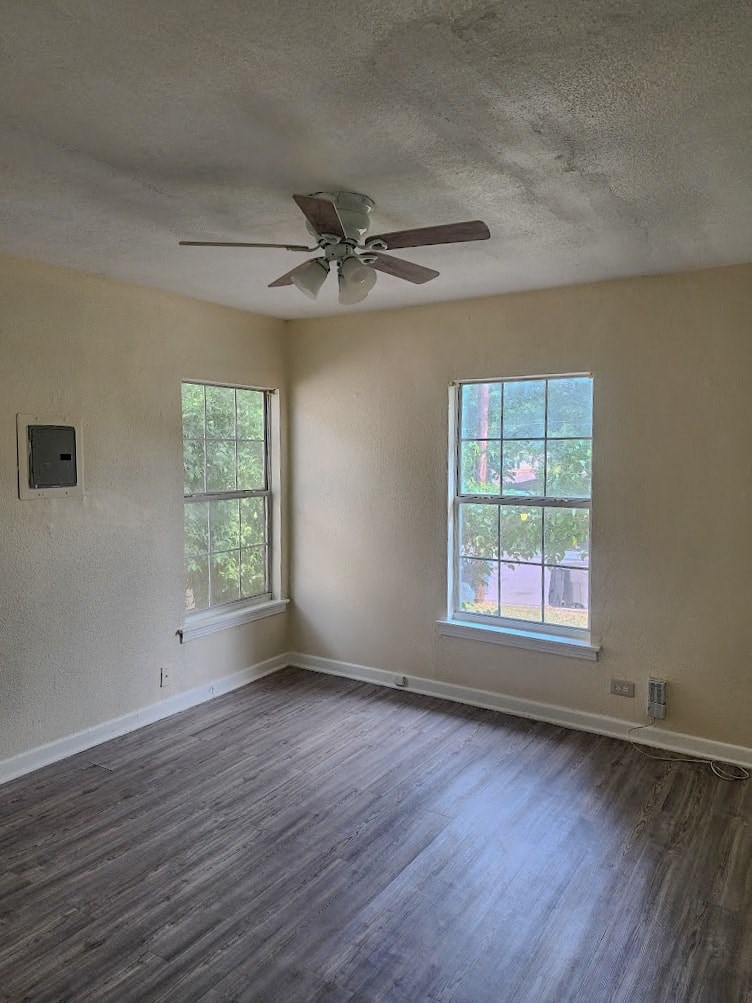 an empty living room with a ceiling fan and a window