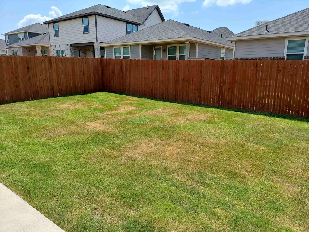 a backyard with a fenced in yard and a house