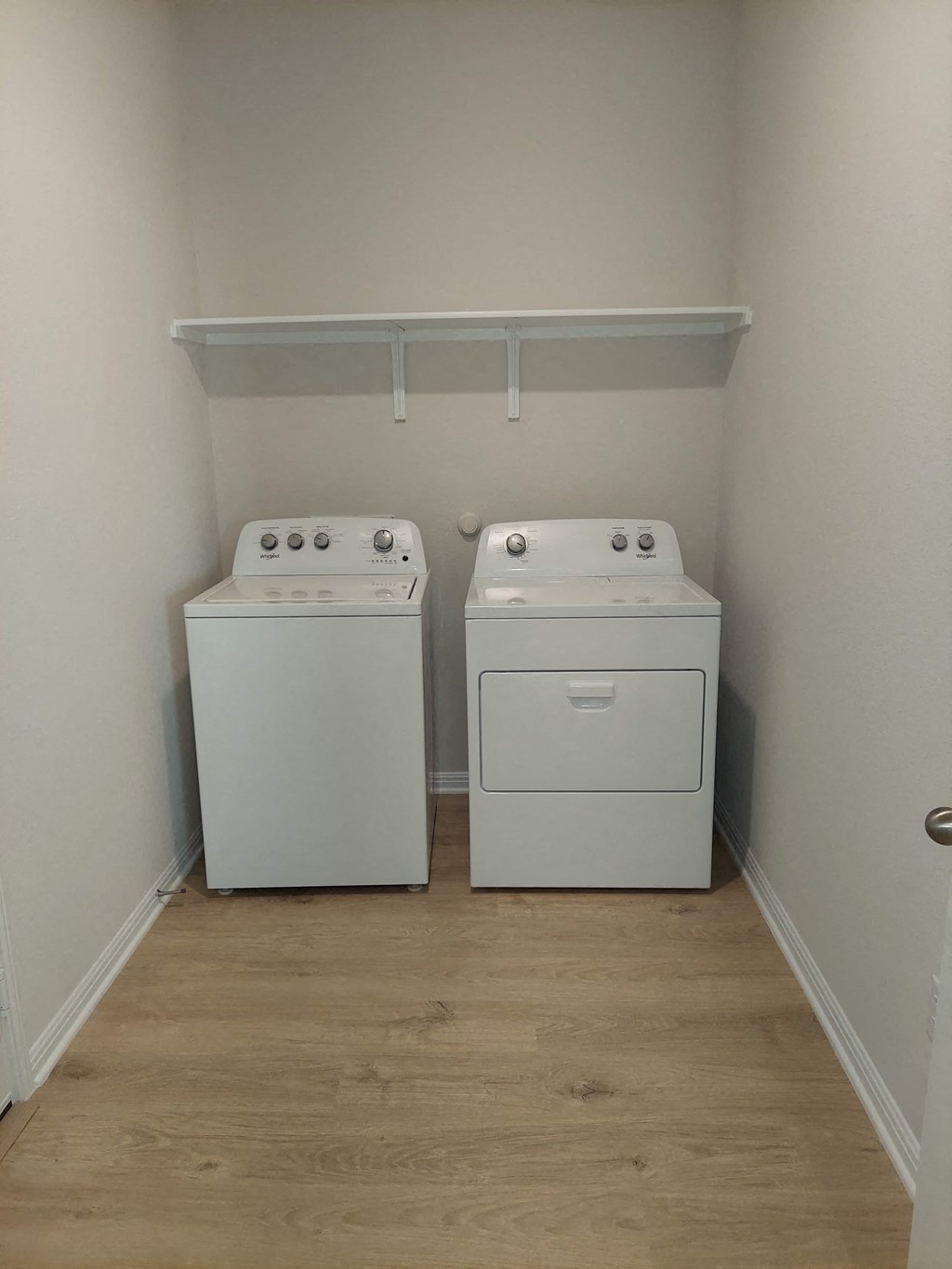 two washers and dryers in a room with a wood floor
