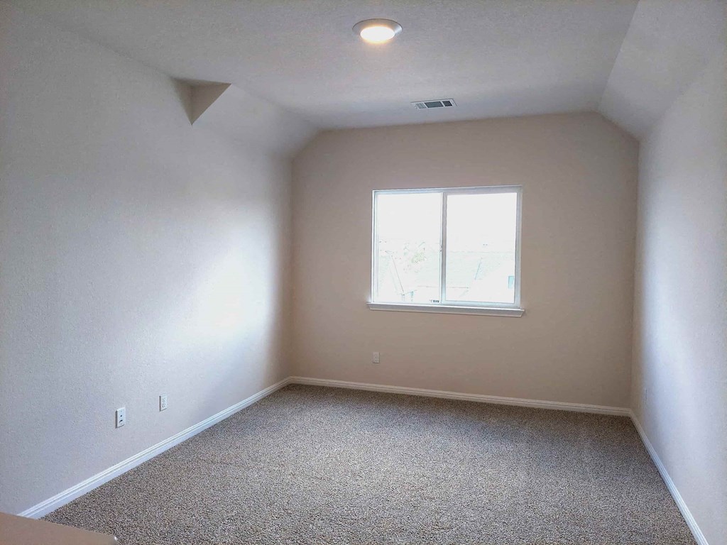 an empty room with a window and carpet