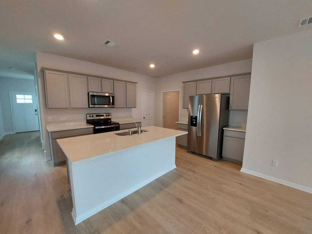a kitchen with a large island and a stainless steel refrigerator