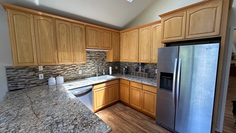 a kitchen with wooden cabinets and a stainless steel refrigerator