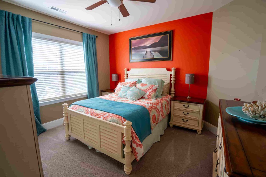 a bedroom with an orange accent wall and a bed with a blue blanket