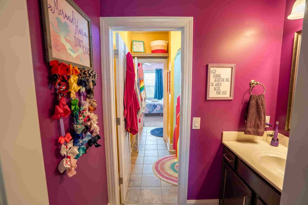 a bathroom with pink walls and a sink and a hallway to a bedroom