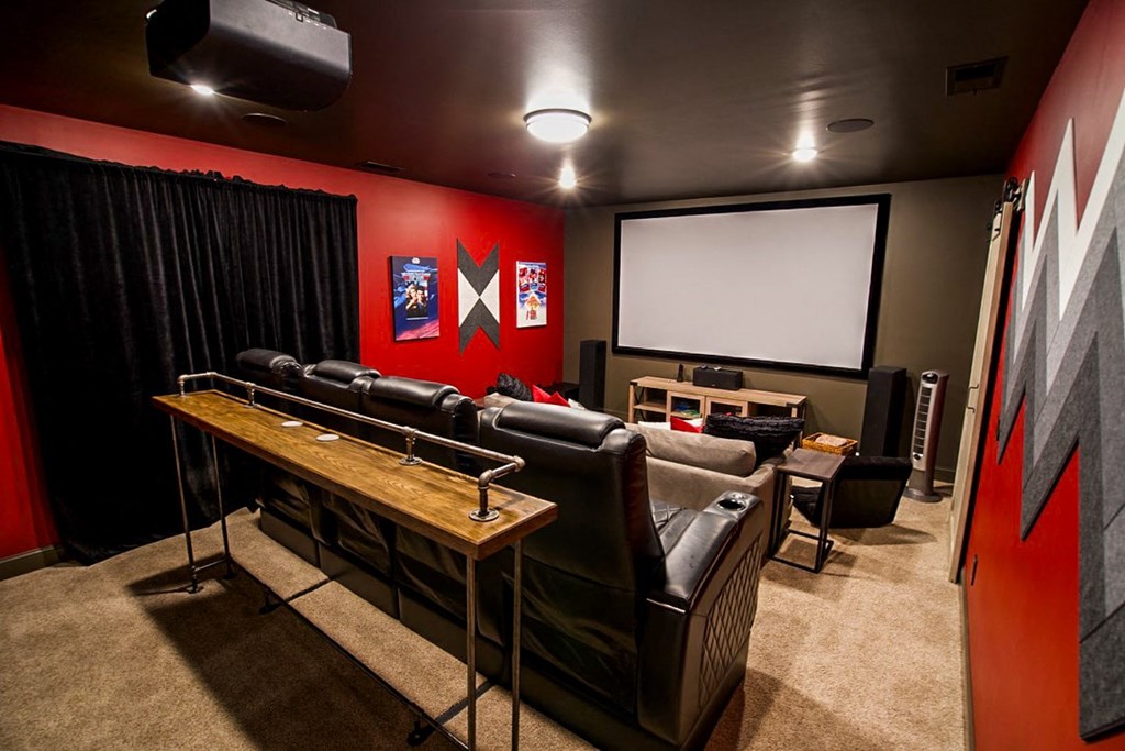 a home theater room with leather seats and a wooden table