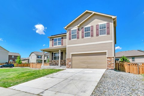 a tan house with a garage door and a driveway