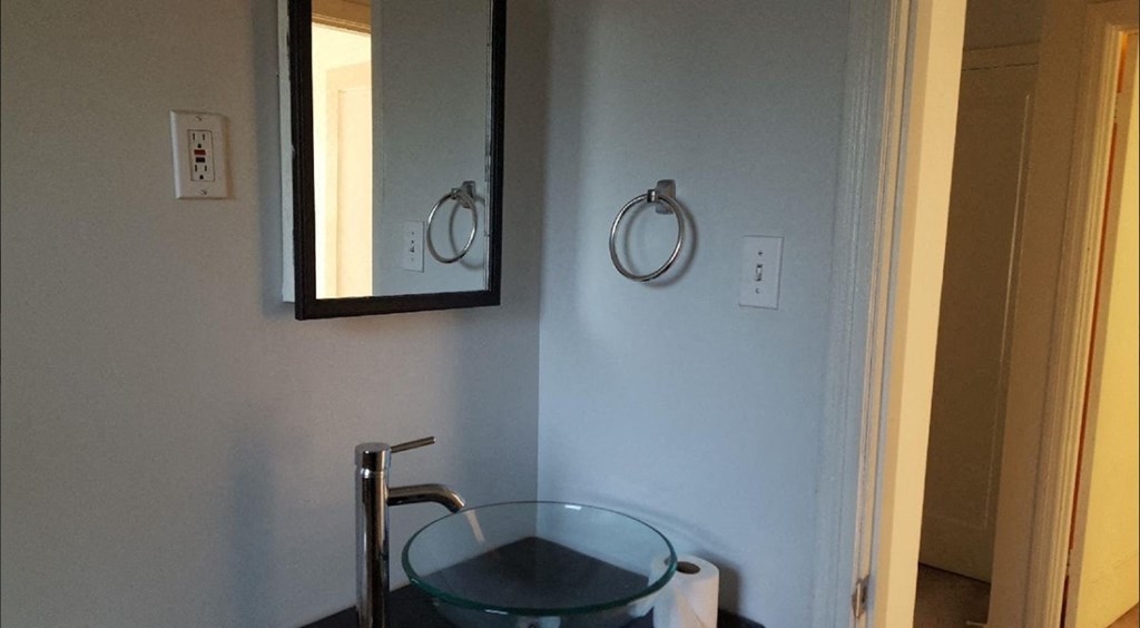 a bathroom with a glass sink and a mirror