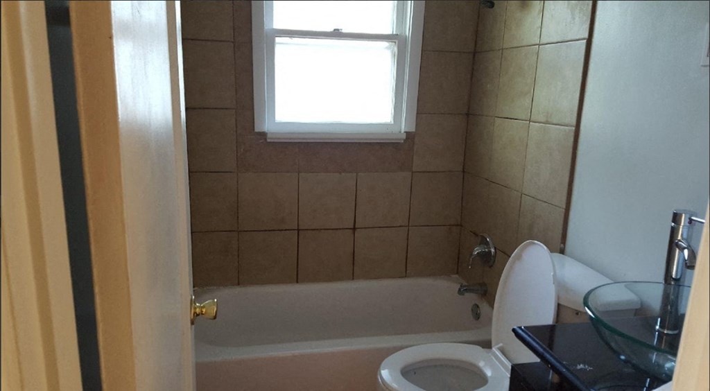 a bathroom with a toilet and a tub and a window