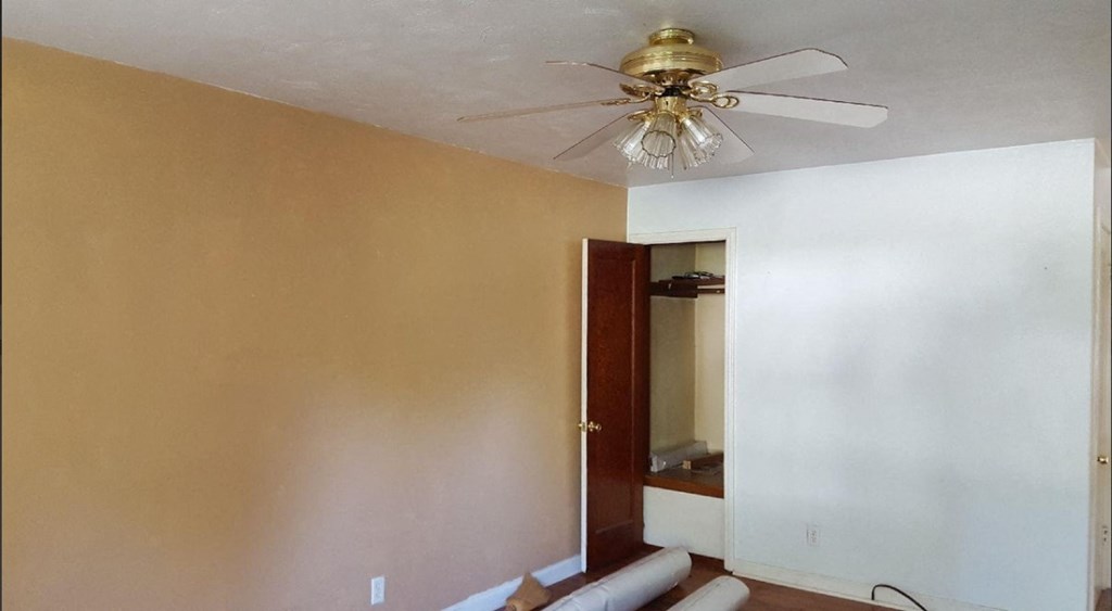 an empty room with a ceiling fan and a door