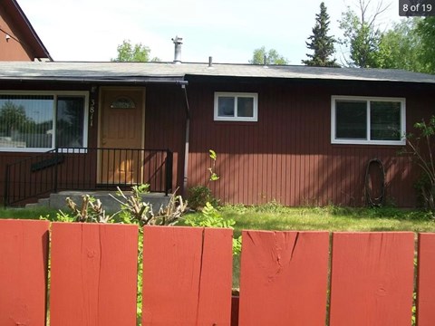 A brown house with a red fence in front.