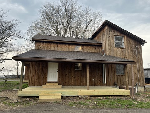 the back of the barn with the porch and steps in front of it