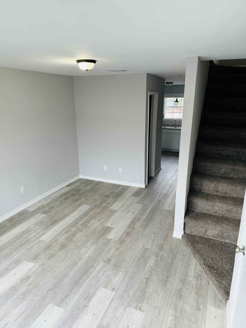 a renovated living room with hard wood floors and a staircase