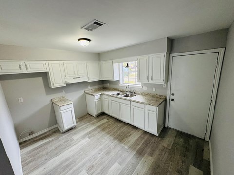 a remodeled kitchen with white cabinets and wood floors