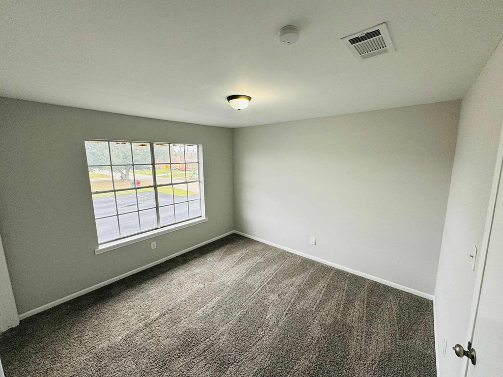 an empty living room with a window and carpet