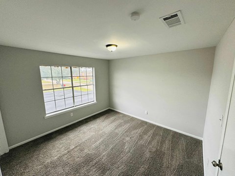 an empty living room with a window and carpet