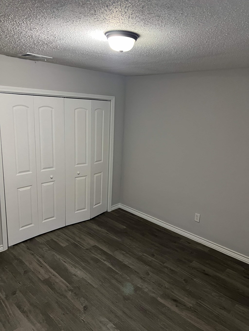 a bedroom with two closets and a wood flooring