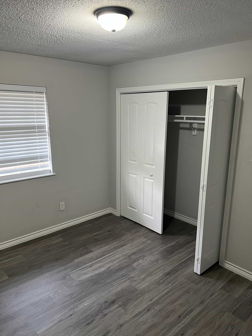 an empty bedroom with a closet and a window
