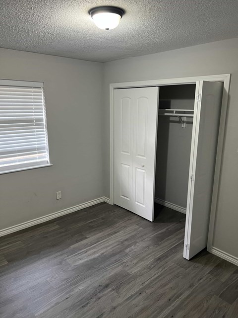 an empty bedroom with a closet and a window