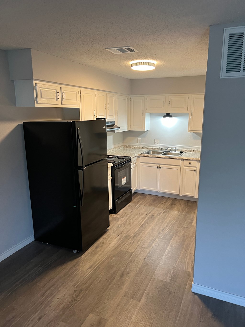 a kitchen with white cabinets and a black refrigerator