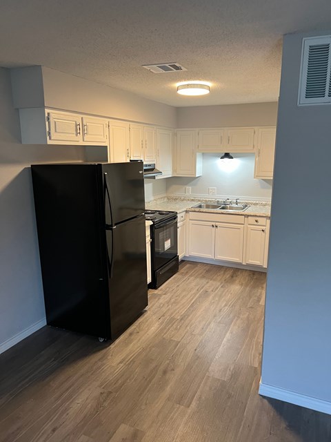 a kitchen with white cabinets and a black refrigerator