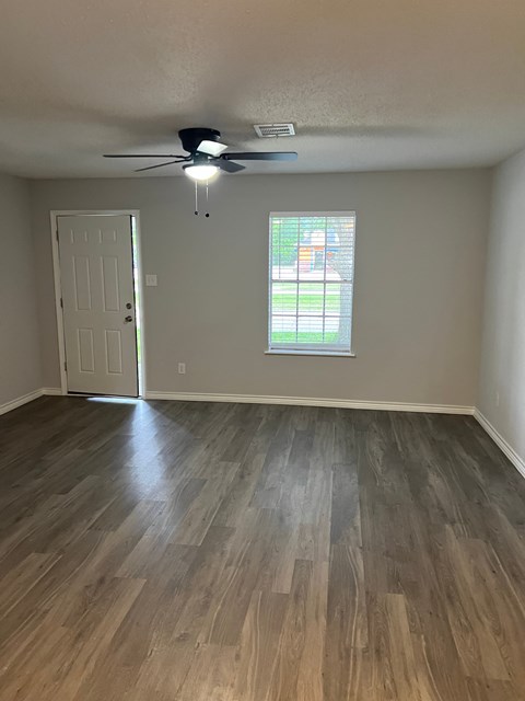 an empty living room with wooden floors and a ceiling fan