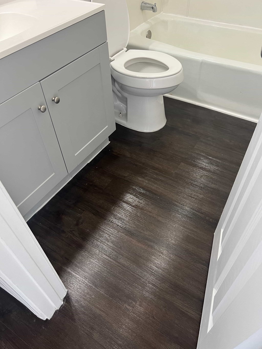a bathroom with a toilet and a bath tub and a wooden floor