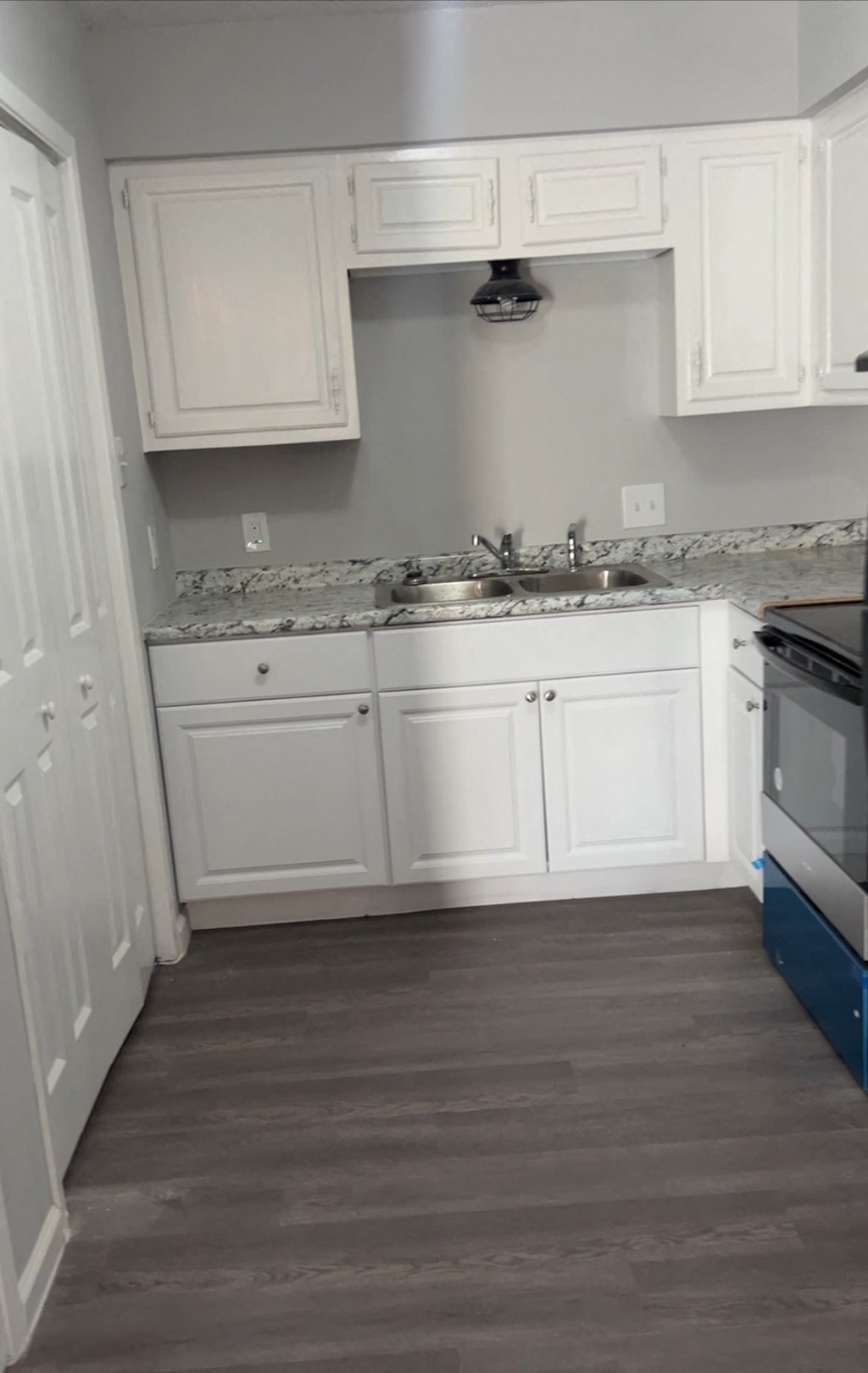 a small kitchen with white cabinets and a wood floor