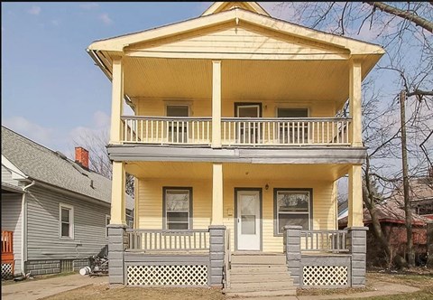 a yellow house with a porch and a white