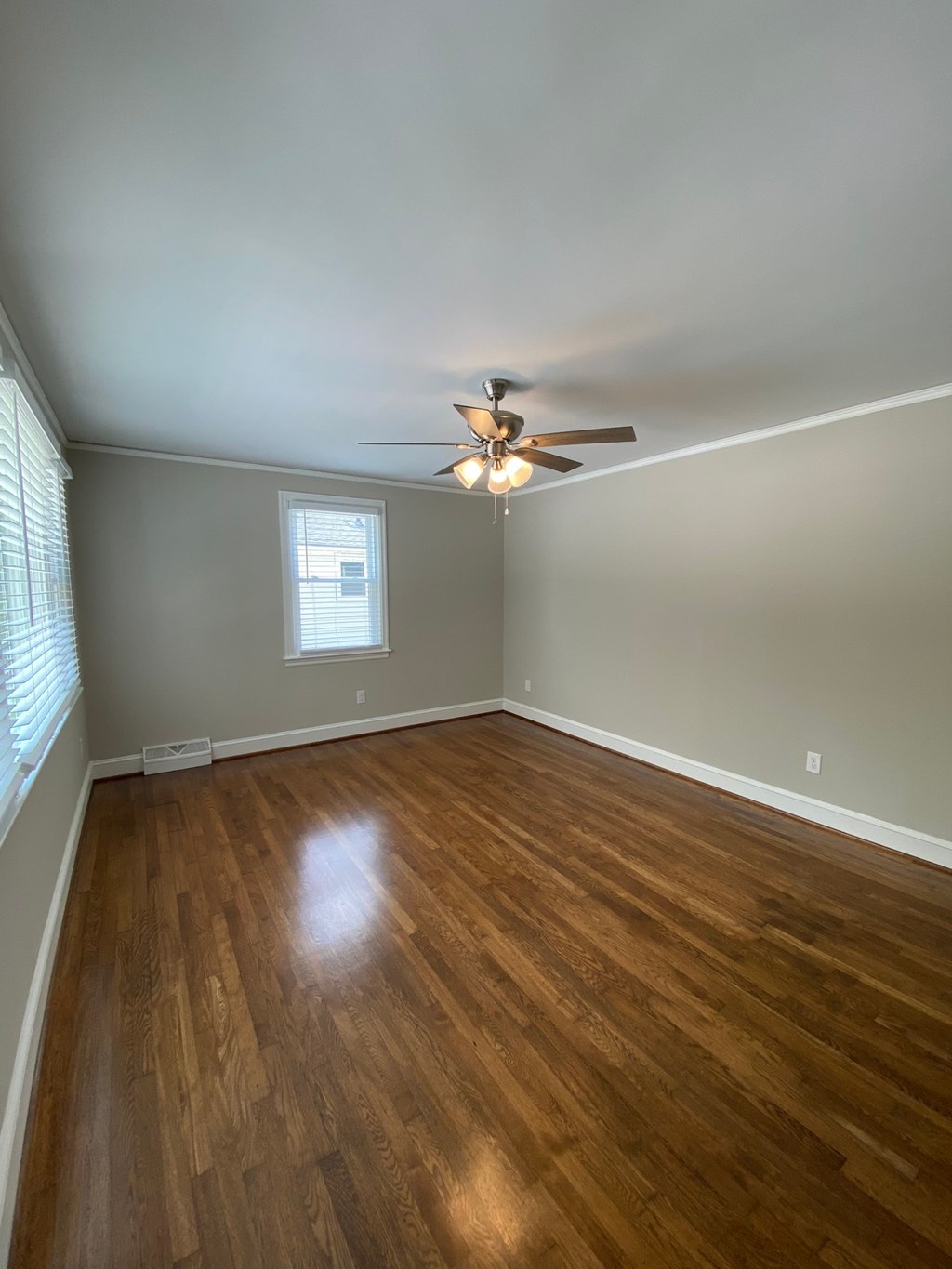 an empty living room with wooden floors and a ceiling fan
