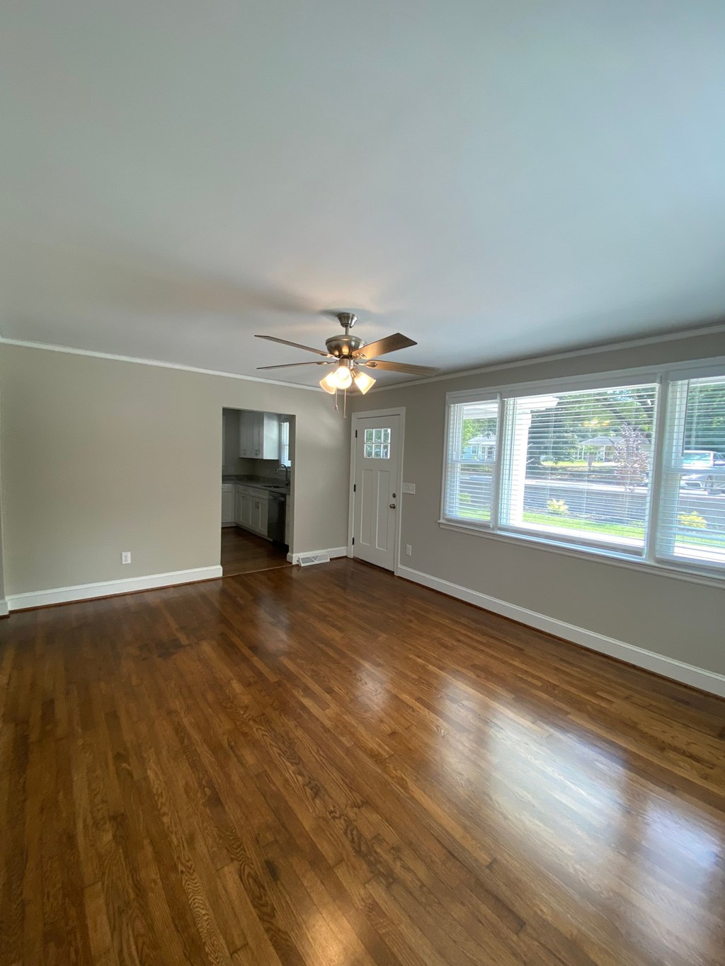 an empty living room with wood floors and a ceiling fan