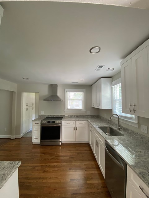 a kitchen with white cabinets and granite counter tops and a sink