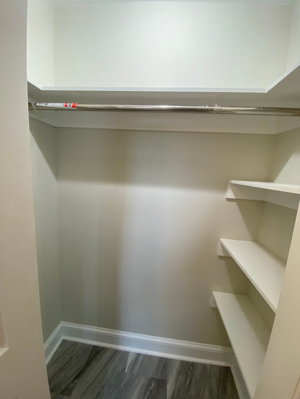 a walk in closet with white shelves and a white wall
