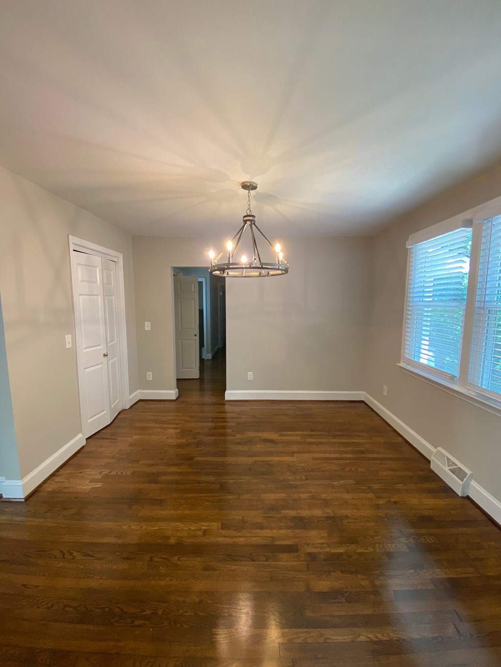 an empty living room with wood floors and a chandelier
