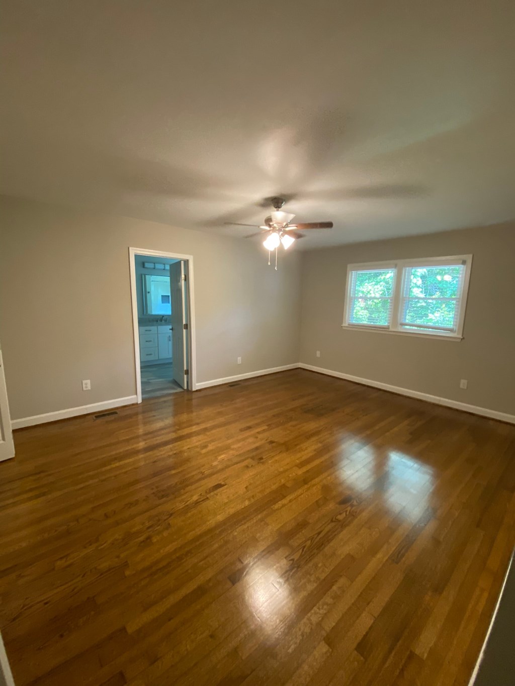 an empty living room with wooden floors and a ceiling fan