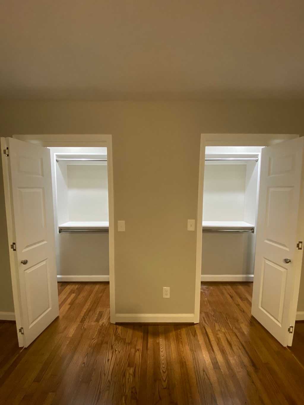 an empty living room with three doors and a wood floor