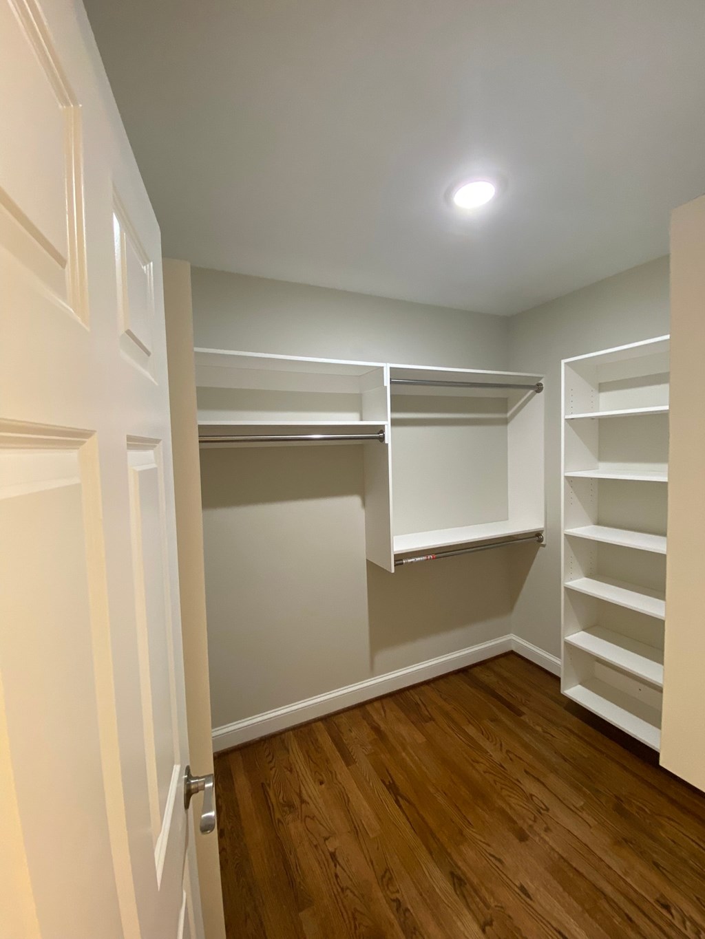 a bedroom with a closet and shelves and a wood floor