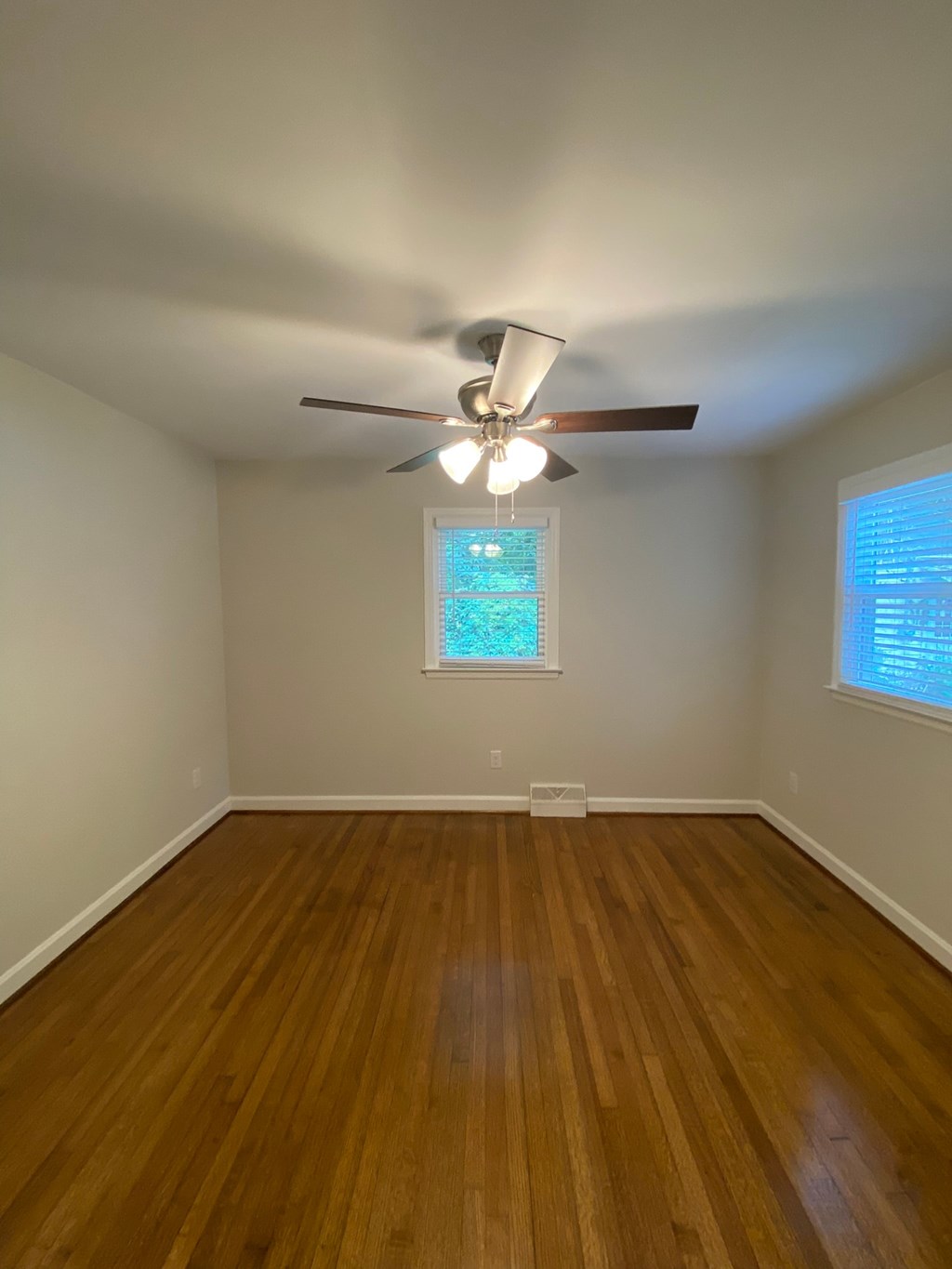 an empty living room with a ceiling fan and wood floors
