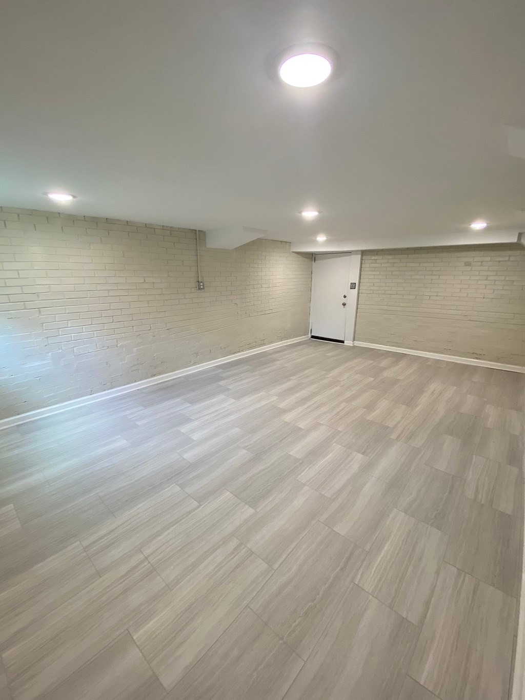 an empty room with wood flooring and a brick wall