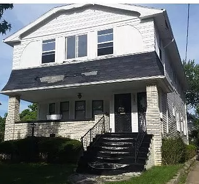A white house with a black front door and stairs.