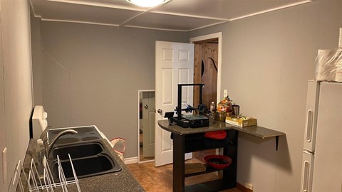 a kitchen with a sink and a refrigerator and a door into a room