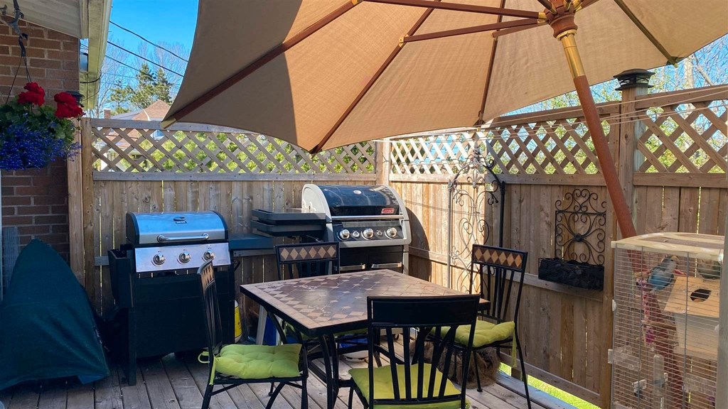 a patio with a table and chairs and a barbecue grill
