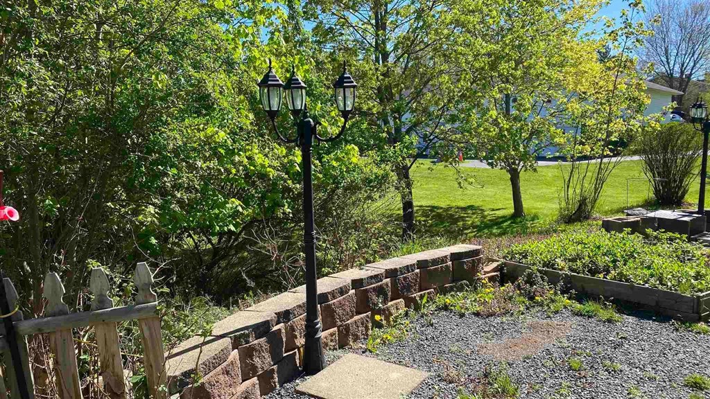a garden with a lamp post and a stone wall