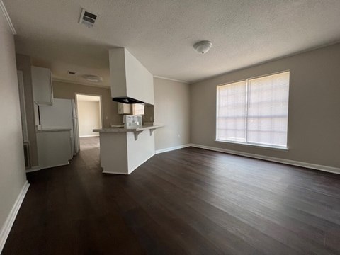an empty living room and kitchen with wood floors