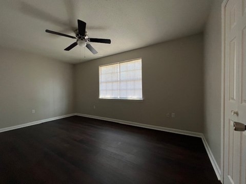 an empty room with a ceiling fan and a window