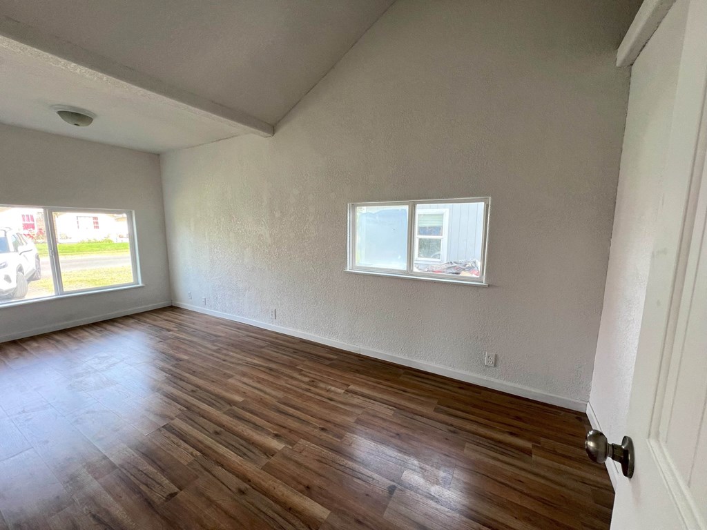 an empty living room with wooden floors and a window