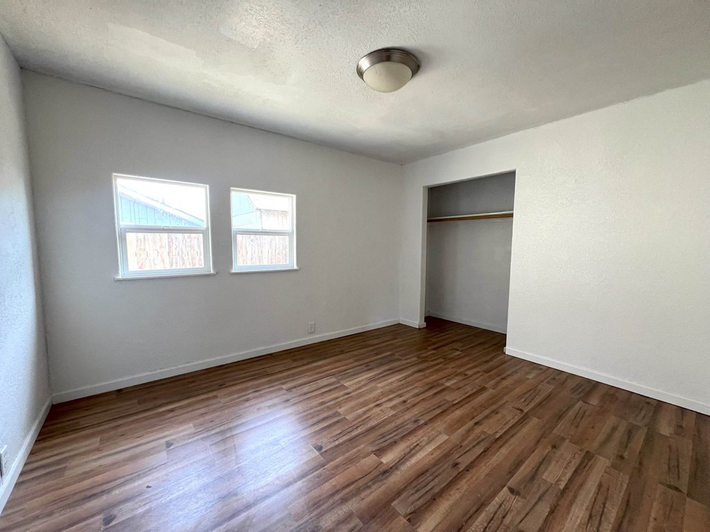 an empty living room with wood flooring and a closet