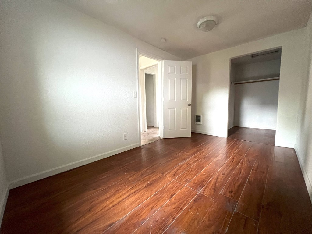 an empty living room with wooden floors and white walls