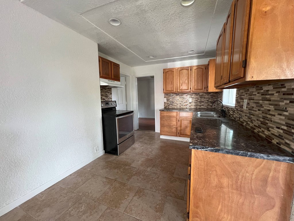 a kitchen with wood cabinets and a black counter top