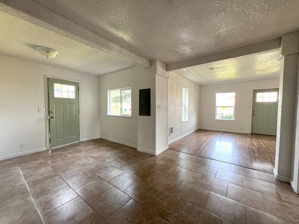 an empty living room with tile floors and a green door