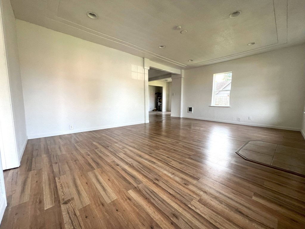 an empty living room with hardwood floors and white walls